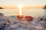Sunglasses on a stone with sun rays during sunset picjumbo com